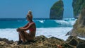 Girl sitting on the Rock and watching Huge Waves hitting Tembeling Coastline at Nusa Penida Island, Bali Indonesia Royalty Free Stock Photo