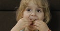 Girl sitting on sofa and eating corn puffs. Child taste puffcorns