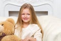 Girl sitting on sofa hugging teddy bear Royalty Free Stock Photo