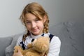 Girl sitting on sofa hugging teddy bear Royalty Free Stock Photo