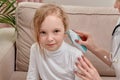 Girl sitting on a sofa, smiling. Check the baby hearing with an otoscope.