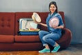 Girl sitting on sofa with suitcase and holding hat Royalty Free Stock Photo