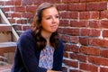 Girl Sitting on Stairway, Next to Red Brick Wall Royalty Free Stock Photo