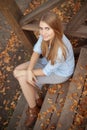 Girl sitting on the steps of the wooden porch, autumn season Royalty Free Stock Photo