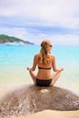 Girl sitting on stone backward near sea