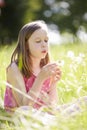 Girl Sitting In Summer Field Blowing Dandelion Plant Royalty Free Stock Photo