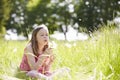 Girl Sitting In Summer Field Blowing Dandelion Plant Royalty Free Stock Photo