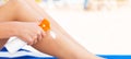 Girl is sitting on the sunbed and applying sun cream oh her leg at the beach Royalty Free Stock Photo