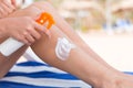 Girl is sitting on the sunbed and applying sun cream oh her leg at the beach Royalty Free Stock Photo