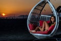 Girl sitting in the swing on the beach in the sunset Royalty Free Stock Photo