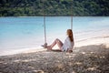 Girl sitting on the swing on the tropical beach Royalty Free Stock Photo