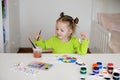 Girl is sitting at a table and drawing a picture on the theme of autism symbol Royalty Free Stock Photo