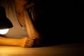 Girl sitting at a table in the light of a table lamp in the dark