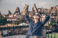 Girl sitting at the table on the roof terrace of cave hotel in Cappadocia, Turkey. Famous mountains and cave buildings