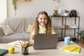 Girl sitting at table, using laptop for e-learning