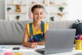 Girl sitting at table, using laptop, writing in notebook Royalty Free Stock Photo