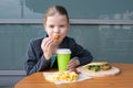 Girl sitting at the table, where the food is fast food, eating shrimp in batter