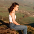 A girl sitting on top of hill against amazing landscape in the summer