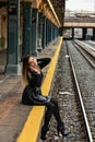 Girl sitting on the train platform while talking on phone.