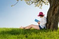 Girl sitting under a blossom tree reads a book Royalty Free Stock Photo