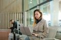 Girl sitting in waiting room with laptop near valise. Royalty Free Stock Photo