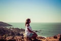 Girl sitting on the wall of the fort on the background of the beach Vagator