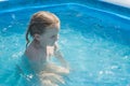 A girl is sitting in the water of an inflatable pool