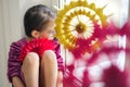 Girl is sitting at window decorated with colorful bright snowflakes