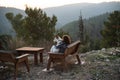 Girl sitting on a wooden bench holding a white dog surrounded by greenery and hills under sunlight Royalty Free Stock Photo