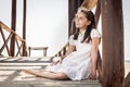 Girl sitting on wooden floor on the beach Royalty Free Stock Photo