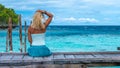 Girl Sitting on Wooden Pier of an Homestay looking into blue ocean, Gam Island, West Papuan, Raja Ampat, Indonesia