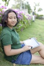 Girl sittingon green grass with computer tablet in hand