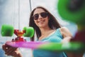 Portrait of cheeful woman in sunglasses holding skateboard