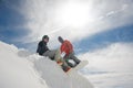 Girl sits on the snow on the hillside , and the guy is getting ready to go down on the snowboard Royalty Free Stock Photo