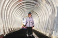 A girl on skis stands on a carpet ski lift in a glass tunel