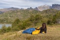 Girl in sleeping bag in mountains near lake