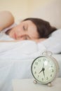 Girl sleeping in her bed with an alarm clock on foreground Royalty Free Stock Photo