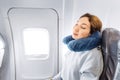 Girl sleeping in her seat on the plane near the window in a mask and with a pillow to sleep. The concept of travel with Royalty Free Stock Photo