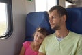 Girl sleeping leaning on dadÃ¢â¬â¢s shoulder in an electric train car
