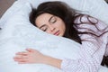 Girl sleeps in a white bed at home. Young woman sleeping in sleepwear on the white linen in bed at home, top view Royalty Free Stock Photo