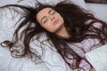 Girl sleeps in a white bed at home. Young woman sleeping in sleepwear on the white linen in bed at home, top view Royalty Free Stock Photo