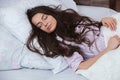 Girl sleeps in a white bed at home. Young woman sleeping in sleepwear on the white linen in bed at home, top view Royalty Free Stock Photo