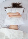 Girl sleeps in a white bed at home. Young woman sleeping in sleepwear on the white linen in bed at home, top view Royalty Free Stock Photo