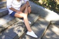 Girl with slender tanned legs sitting on the steps