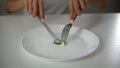 Girl slicing cucumber, obsessed with undereating, fear of overweight, anorexia