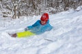 The girl slid down the hill into a snowdrift and squeezed her eyes from the snow flying into her face