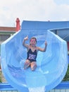 Girl sliding down on a water slide into plunge pool in aqua park. Vacation concept. Holiday fun Royalty Free Stock Photo