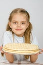 Girl with a slight smile holding a pizza crust on a plate