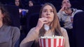 Girl slowly puts the popcorn in her mouth at the movie theater Royalty Free Stock Photo