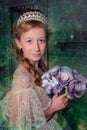 A girl in a smart white dress with a diadem in her hair and a bouquet of flowers in her hands